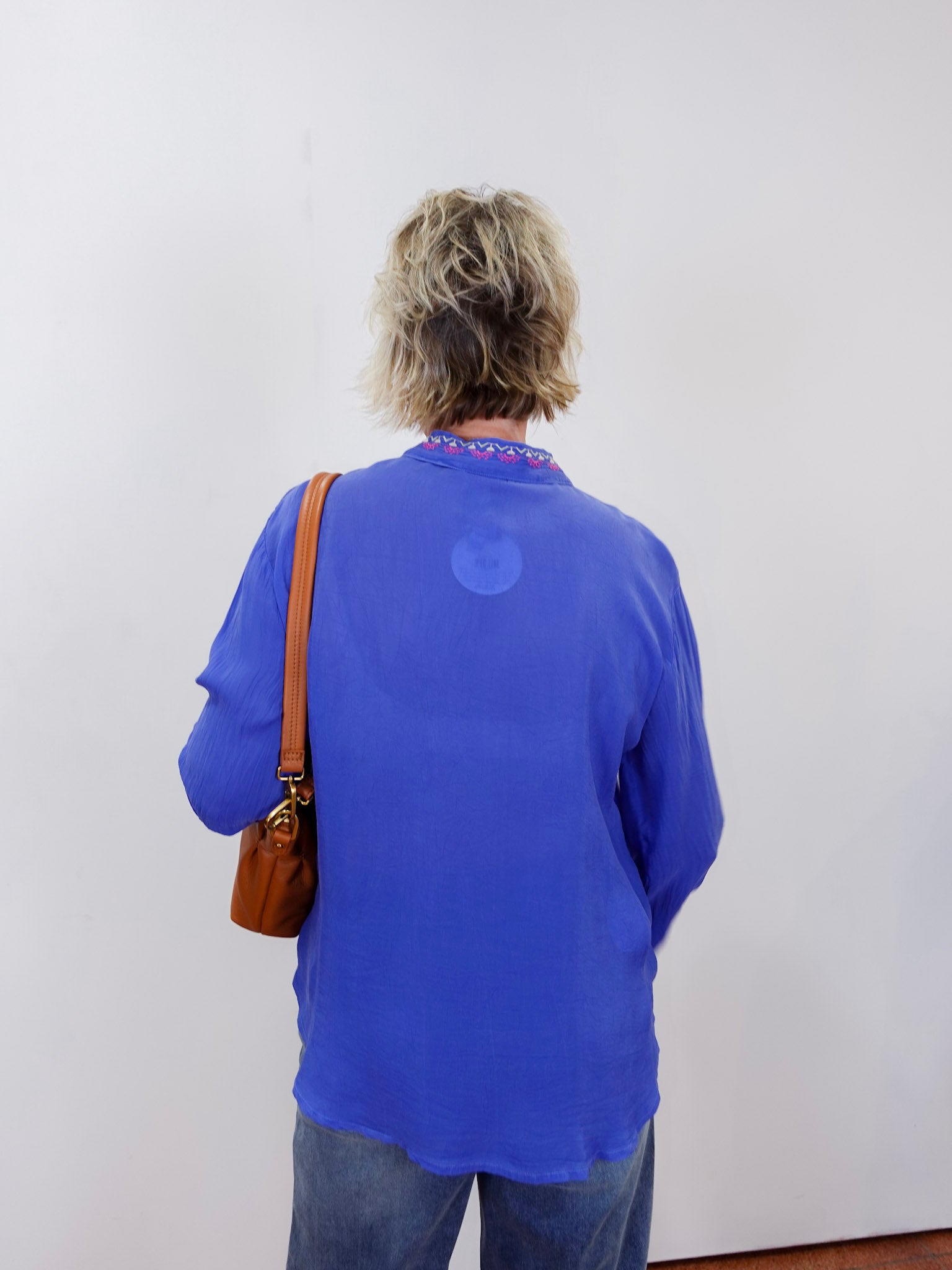 luisa shirt featuring blue fabric with pink and red embroidery worn by model