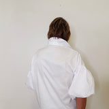 Person wearing a white shirt against a plain background