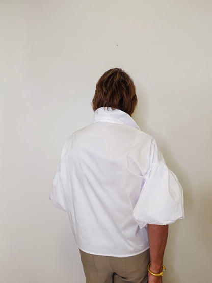 Person wearing a white shirt against a plain background