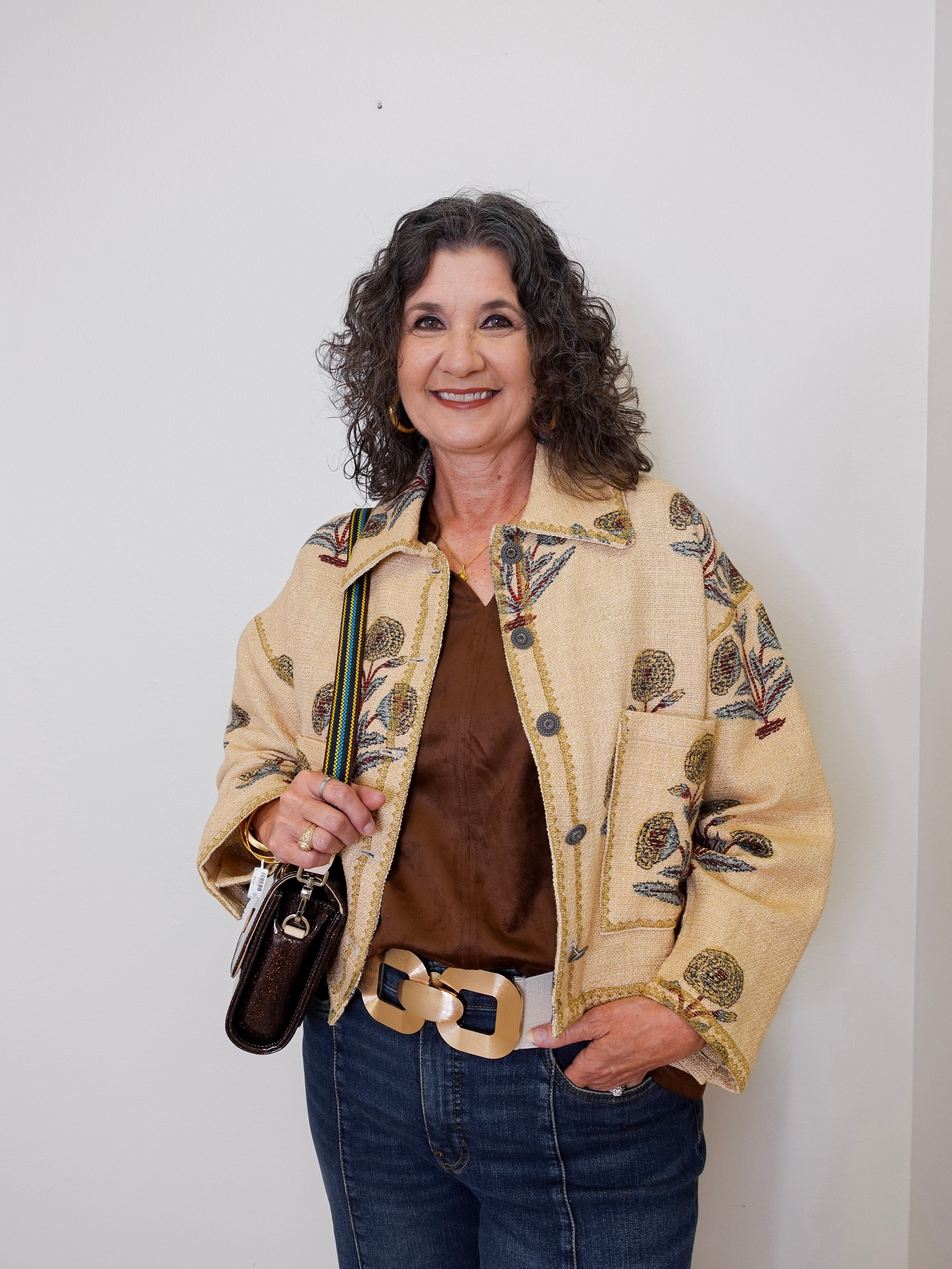 Woman wearing a patterned beige jacket against a white background