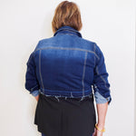 Person wearing a blue denim jacket against a white background