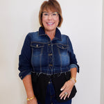 Woman wearing a denim jacket and black top against a white background
