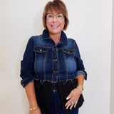 Woman wearing a denim jacket and black top against a white background