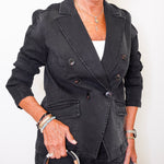 Woman wearing a black jacket holding a black handbag against a white background