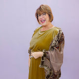 Woman wearing a green dress with a textured shawl against a light purple background