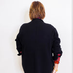 Person wearing a black jacket with colorful cuffs on a white background
