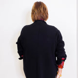Person wearing a black jacket with colorful cuffs on a white background