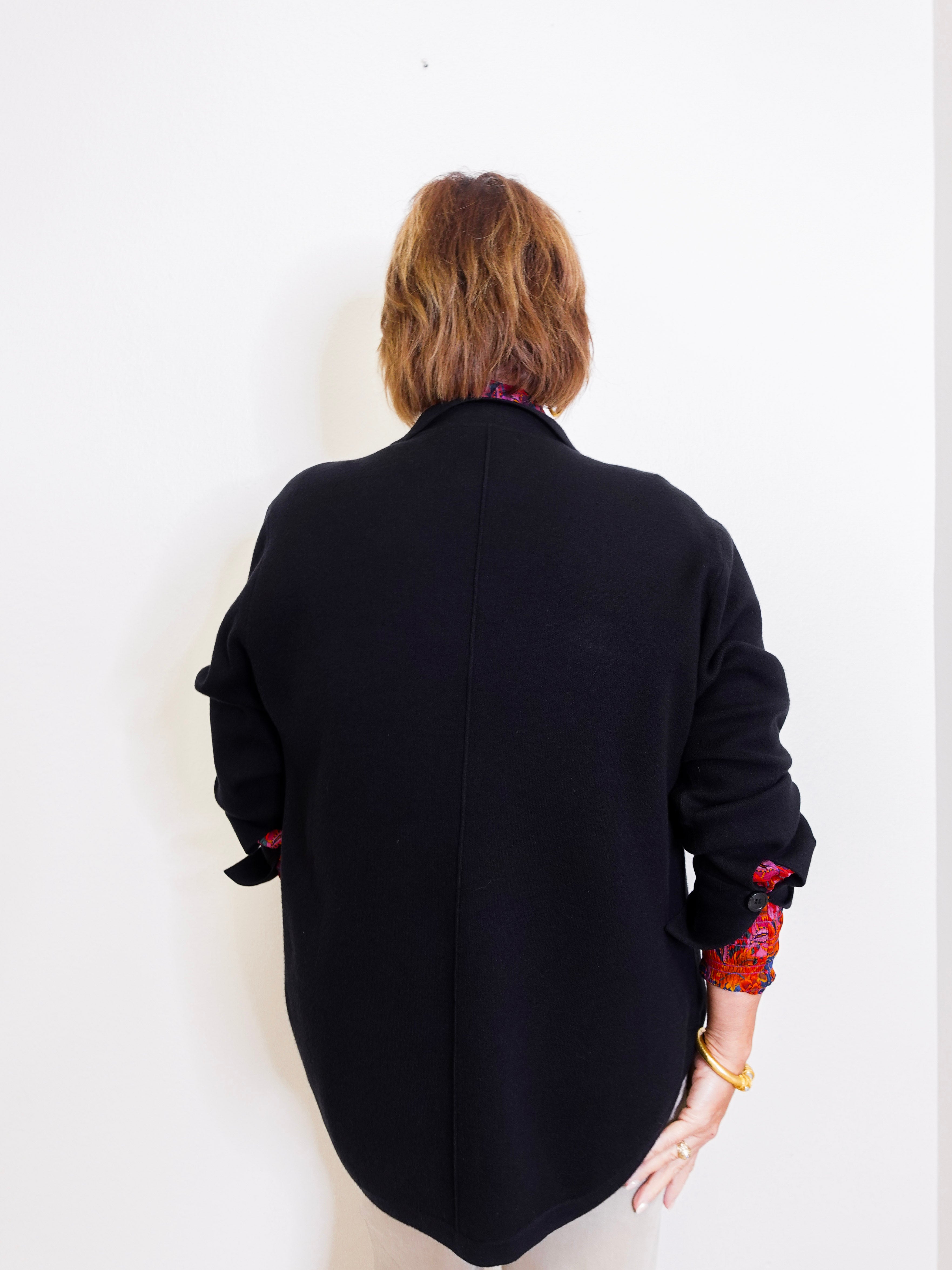 Person wearing a black jacket with colorful cuffs on a white background