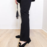 Person wearing black pants and loafers on a light wooden floor.