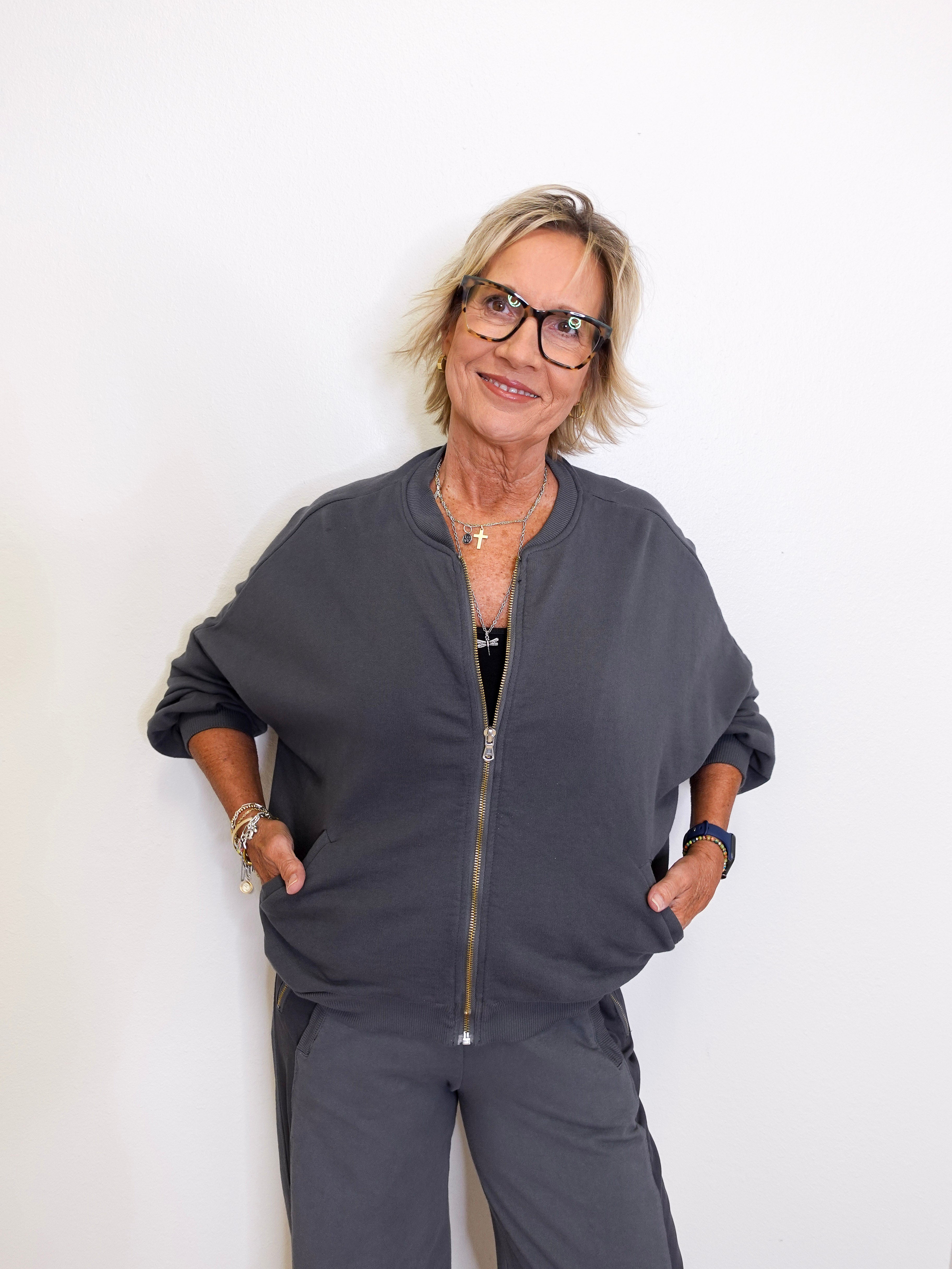 Person wearing a gray zip-up hoodie and pants against a white background