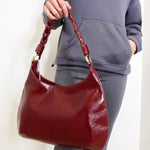 Person holding a red handbag against a plain background