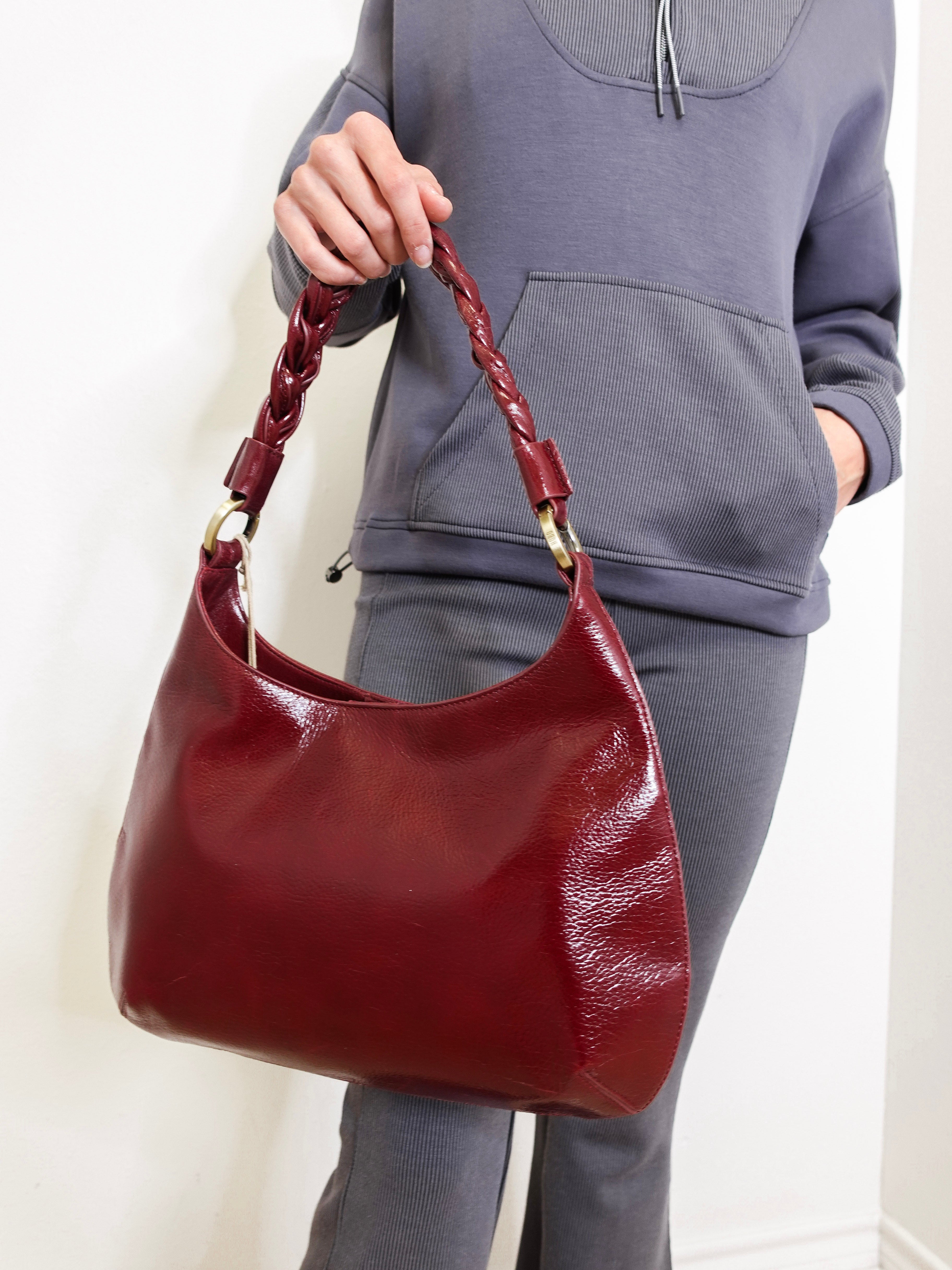 Person holding a red handbag against a plain background