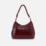 Maroon handbag with braided handle on a light gray background