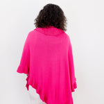 Person wearing a bright pink poncho over a white outfit on a plain background