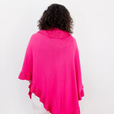 Person wearing a bright pink poncho over a white outfit on a plain background