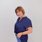 Woman wearing a navy blue top and blue jeans against a white background