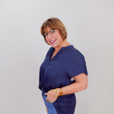 Woman wearing a navy blue top and blue jeans against a white background