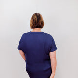 Person wearing a navy blue shirt and pants against a plain background