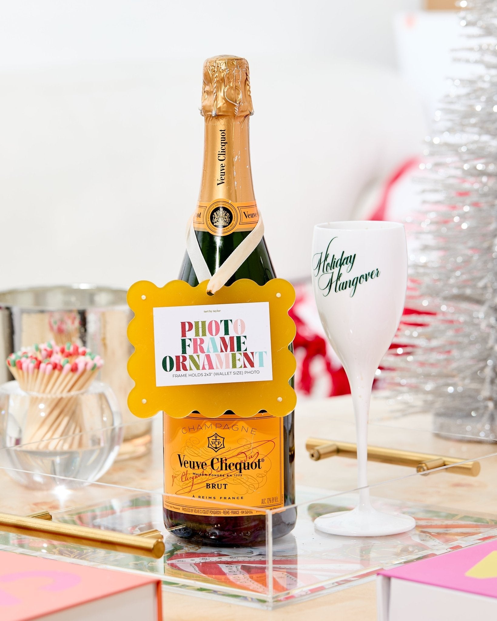 Veuve Clicquot champagne bottle with a decorative label on a table with a glass and other items.