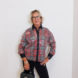 Person wearing a plaid shirt and holding a black handbag against a white background