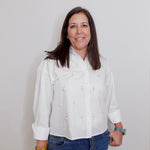 Woman wearing a white blouse and blue jeans against a plain background