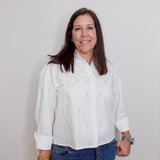 Woman wearing a white blouse and blue jeans against a plain background