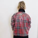 Person wearing a red and black plaid jacket with sequin details on a white background