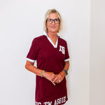 Woman wearing a maroon dress with 'Big 'Em Aggies' text against a white background