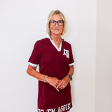 Woman wearing a maroon dress with 'Big 'Em Aggies' text against a white background