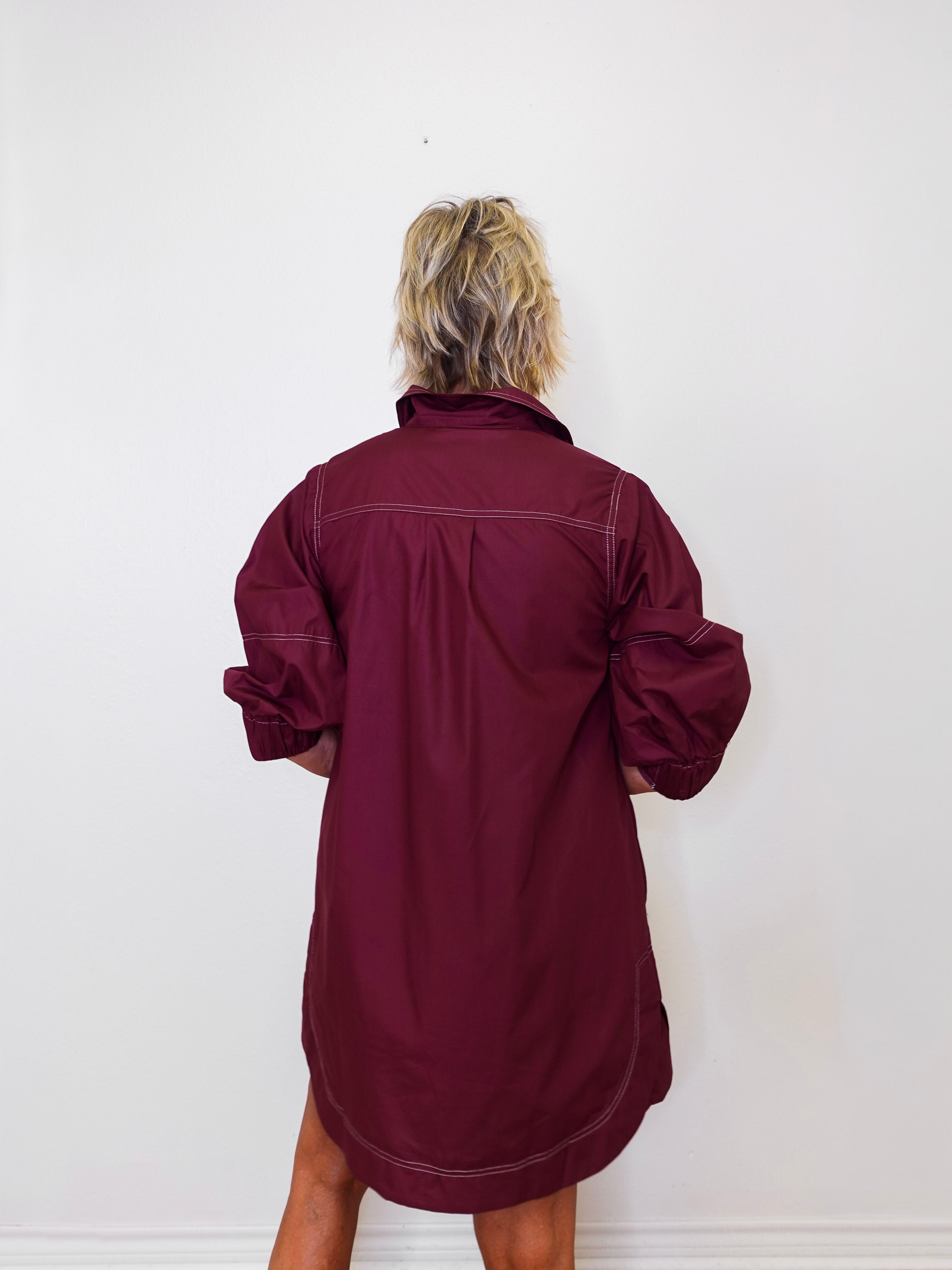Person wearing a burgundy dress against a white background