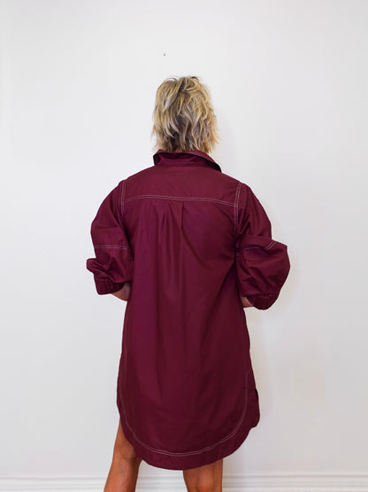 Person wearing a burgundy dress against a white background