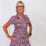 Woman wearing a patterned dress and glasses against a white background