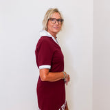 Woman wearing a maroon dress with white text against a white wall