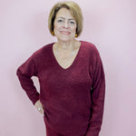 Woman wearing a maroon sweater and pants against a light pink background