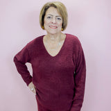 Woman wearing a maroon sweater and pants against a light pink background