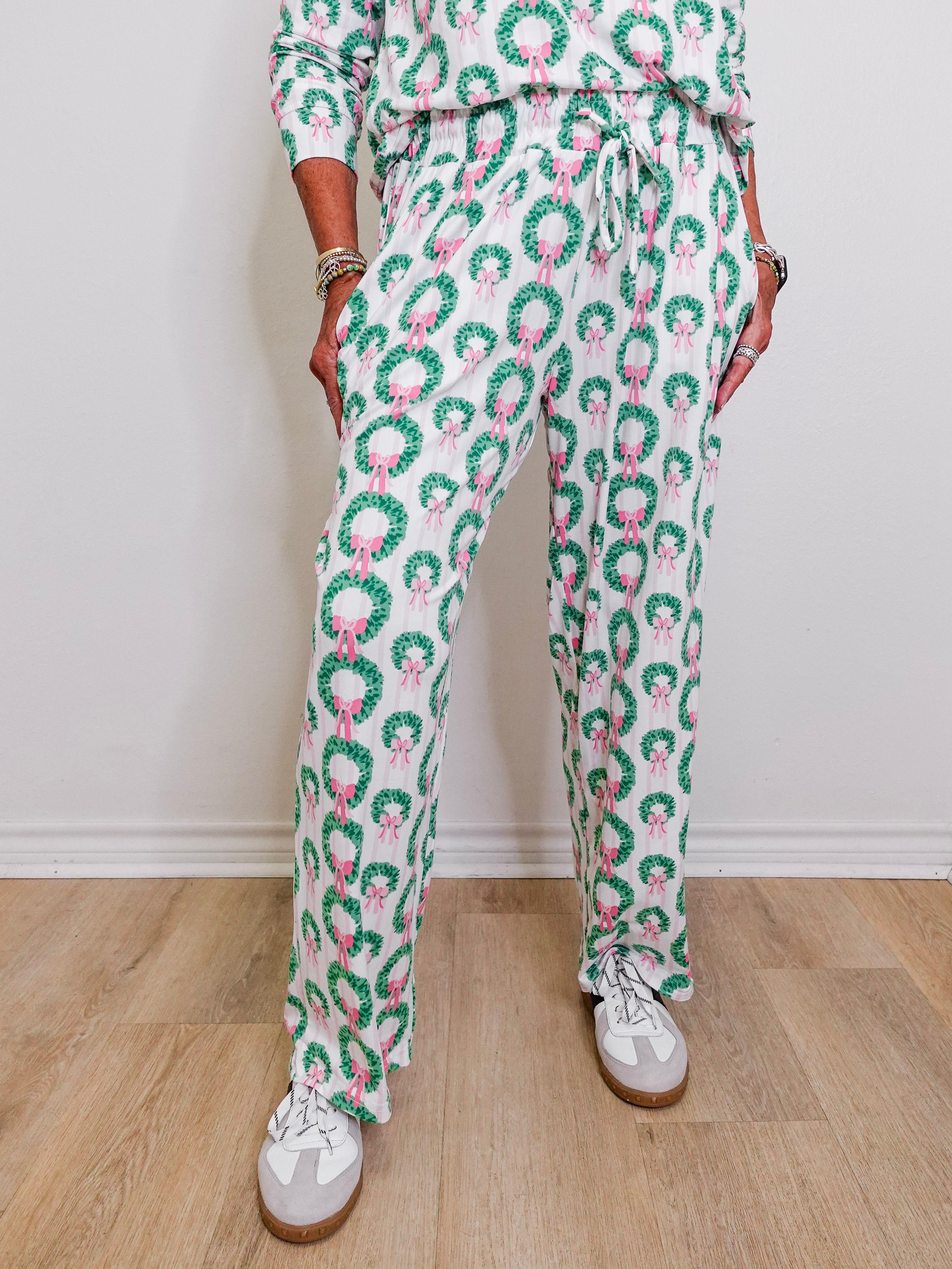 Person wearing a green and pink patterned outfit with white sneakers on a wooden floor.