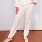 Person wearing a white pajama set with pink patterns on a plain background