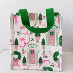 Small tote bag with festive design featuring green trees, pink ribbons, and wreaths on a white background.