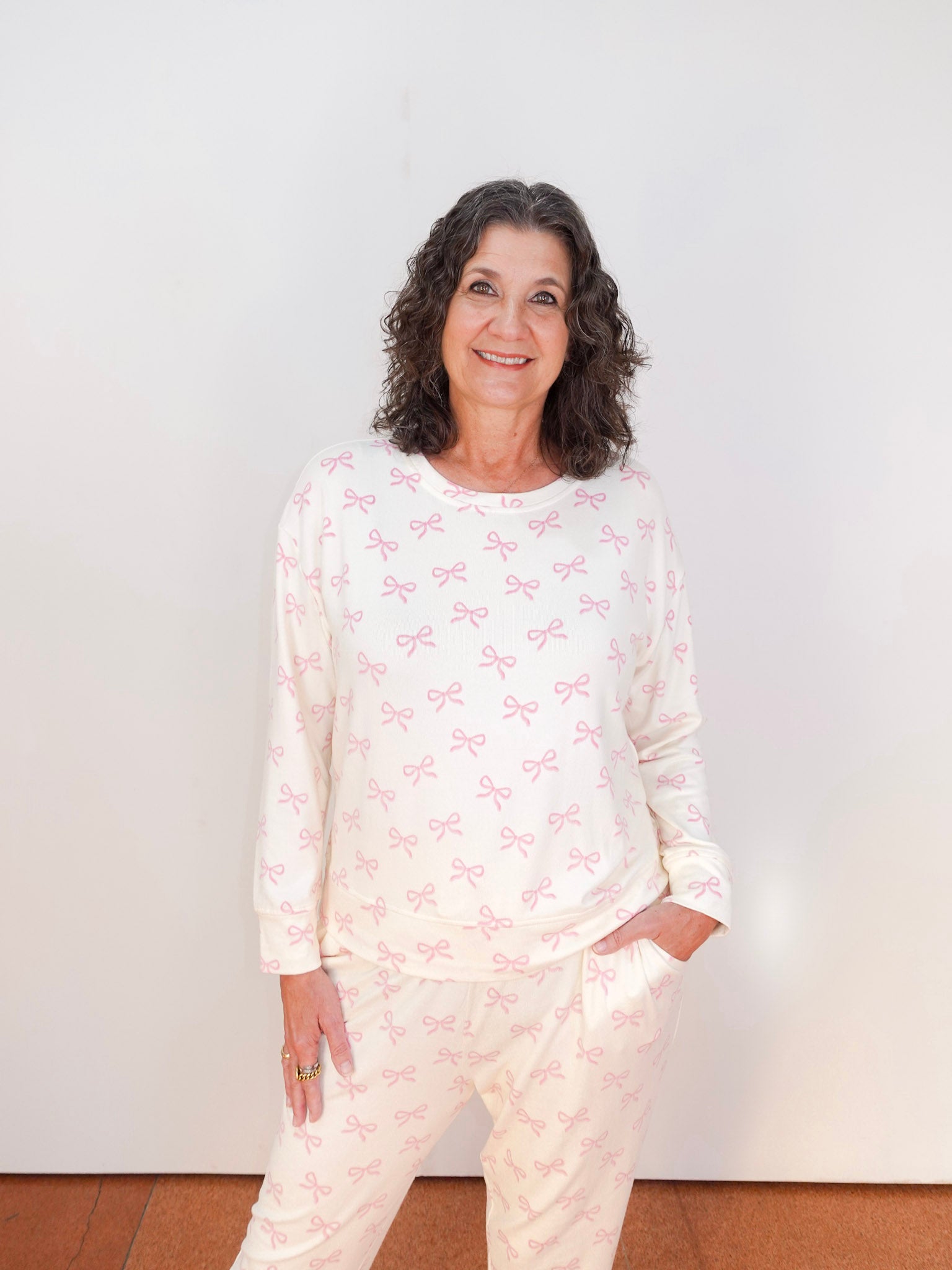 Woman wearing a light-colored pajama set with a subtle pattern against a plain background