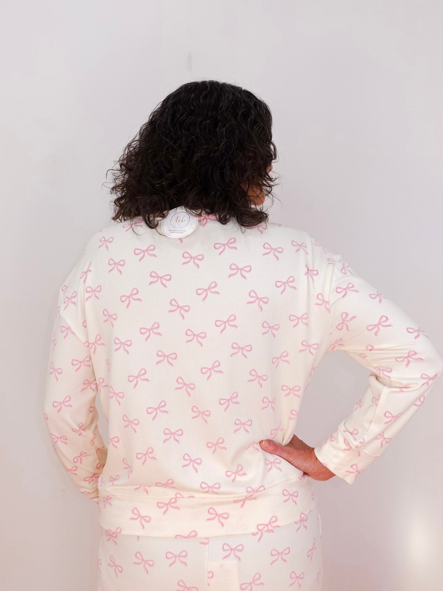 Person wearing a white outfit with pink bow pattern against a plain background