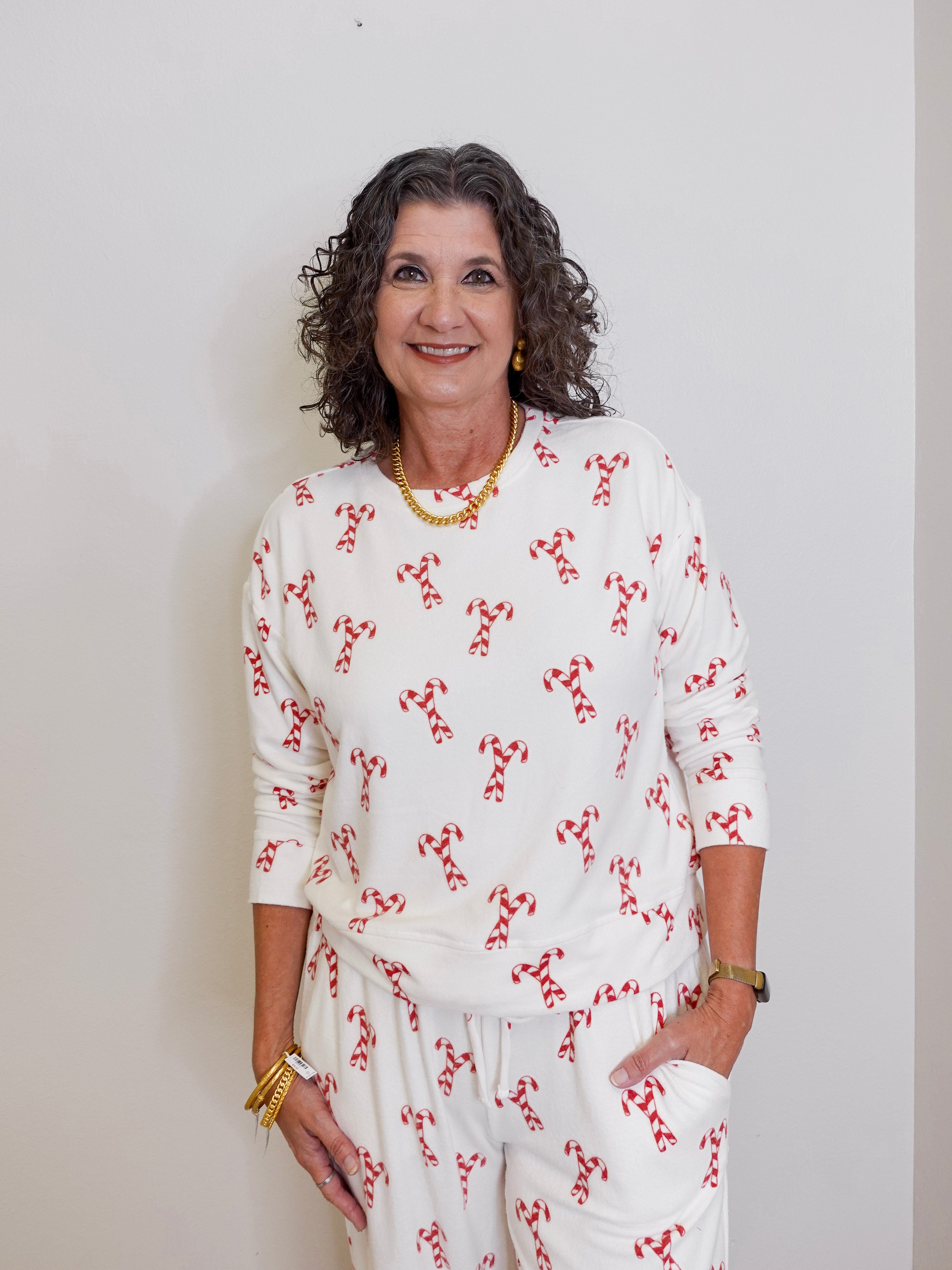 Woman wearing a white outfit with red patterns against a plain background