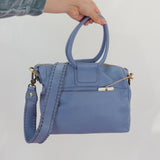 Blue handbag held by a person against a white background
