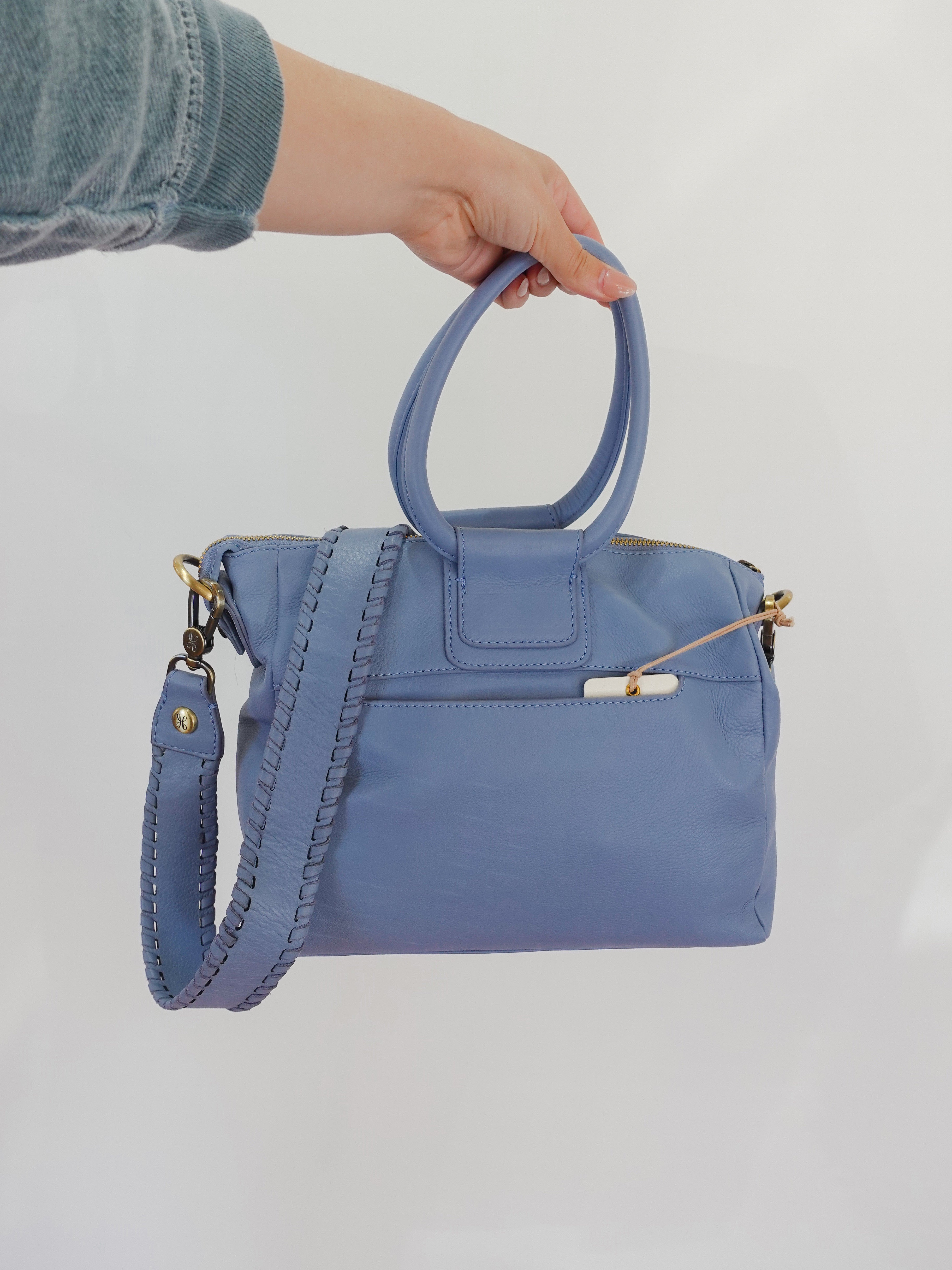 Blue handbag held by a person against a white background
