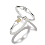 Two silver bangles with gold accents on a white background