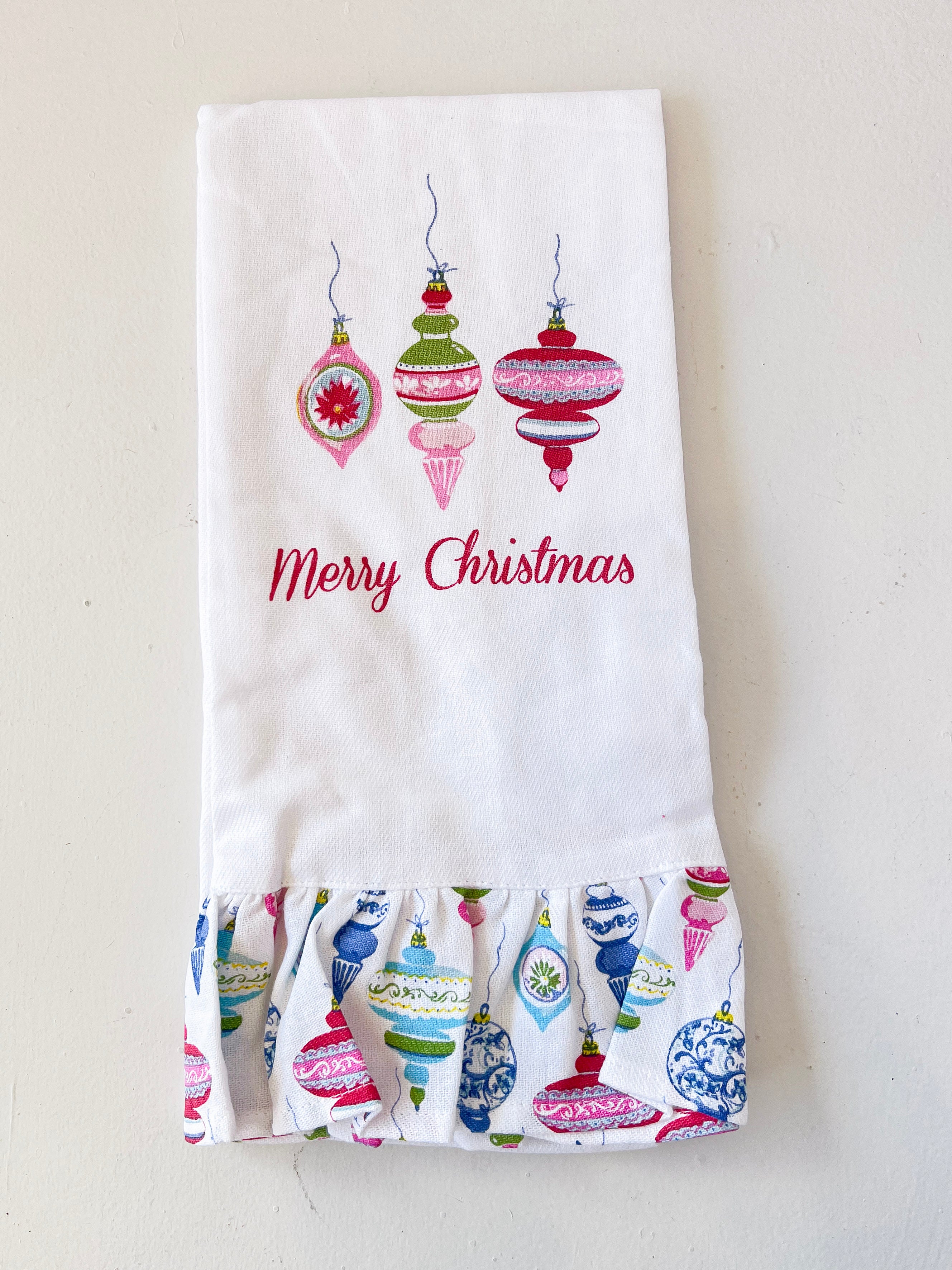White towel with colorful Christmas ornament design and 'Merry Christmas' text on a light gray background