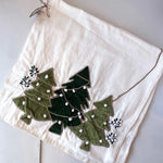 Decorative white towel with green holly leaves and berries on a light wooden surface