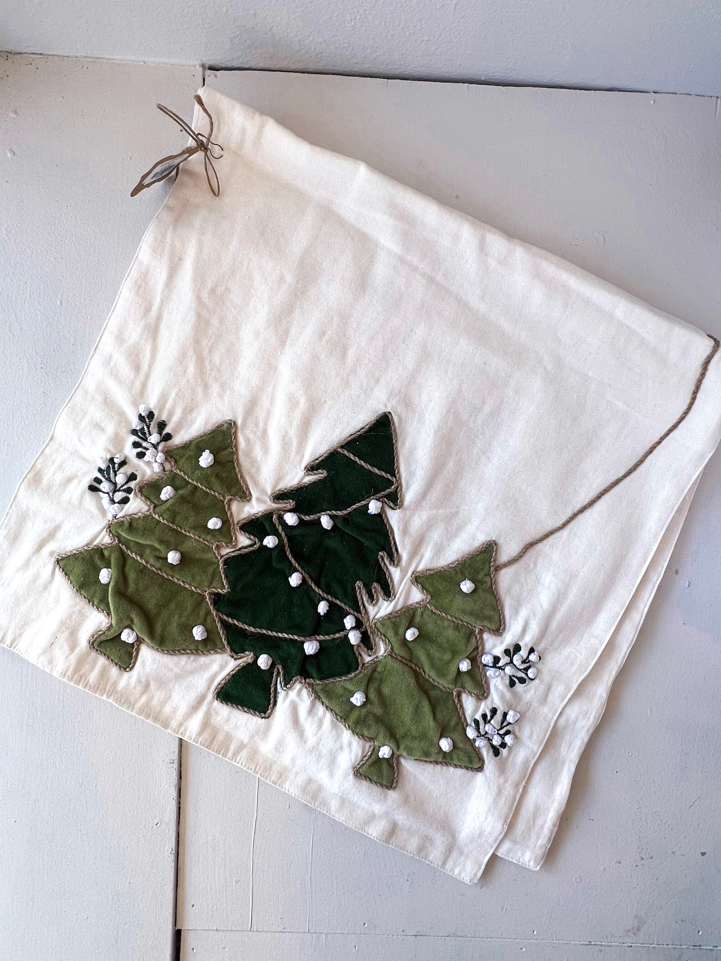 Decorative white towel with green holly leaves and berries on a light wooden surface