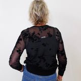 Woman styling a black 2-piece mesh cardigan and tank set with blue jeans, accessorized with a maroon purse.