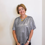 Woman wearing a silver metallic top against a white background