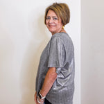Woman wearing a gray t-shirt standing against a white wall